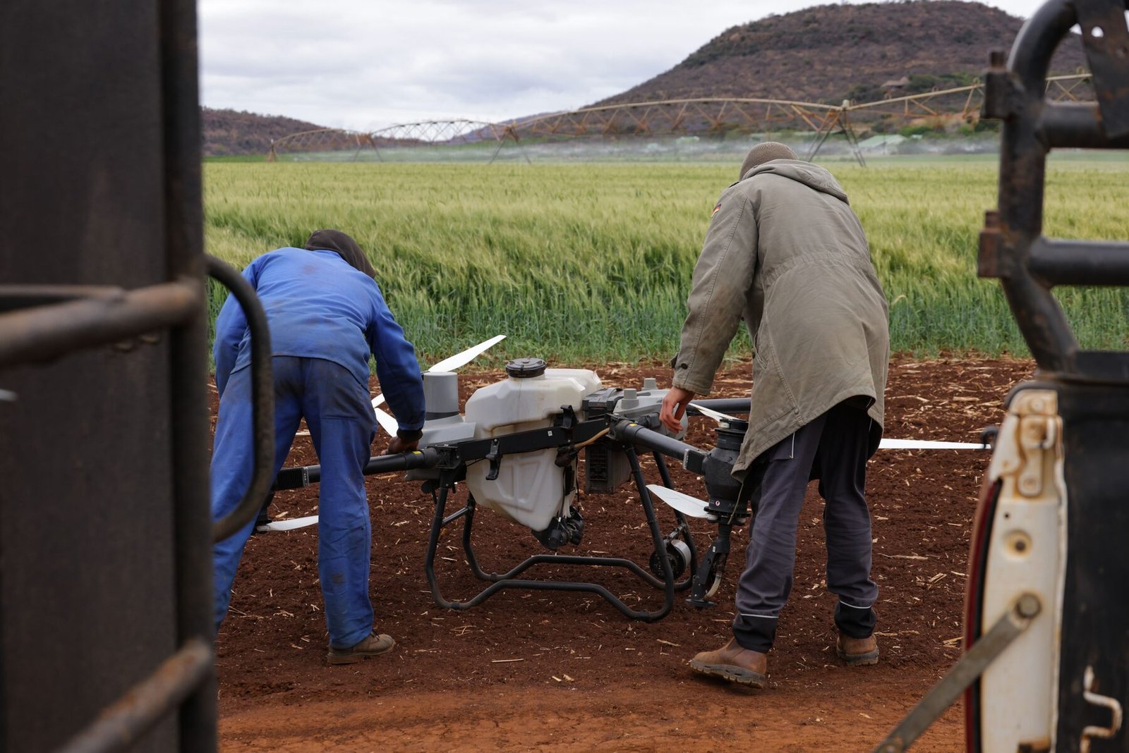 Dva operatora pripremaju poljoprivredni dron na parceli